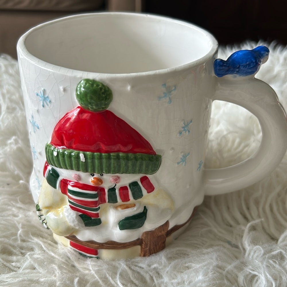 Snowman mug with blue bird thumb rest on handle.